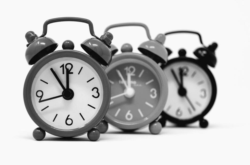 Monochrome image of three vintage alarm clocks highlighting the passage of time.